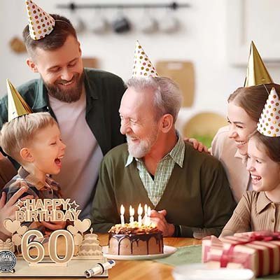 The family was celebrating Grandpa's 60th birthday. The cake was decorated with lit candles, everyone was wearing party hats, and everyone was all smiles.